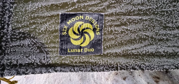 close up of Lunar Duo Backpacking Tent By Six Moon Designs logo during an ice storm on trail during a backpacking tri