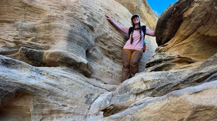  Rear view of a hiker wearing Fjällräven Keb Trousers Curved and a backpack while walking through a red rock canyon in the Southwest.