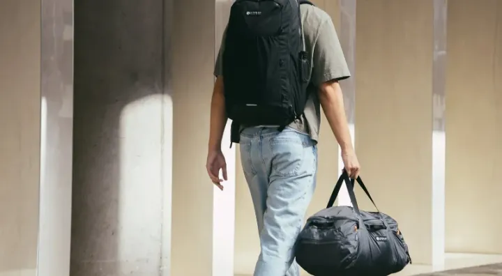 Person walking with Gossamer Gear Aero Jet backpack and duffel bag from the new travel collection, showcasing lightweight travel gear in an urban setting.