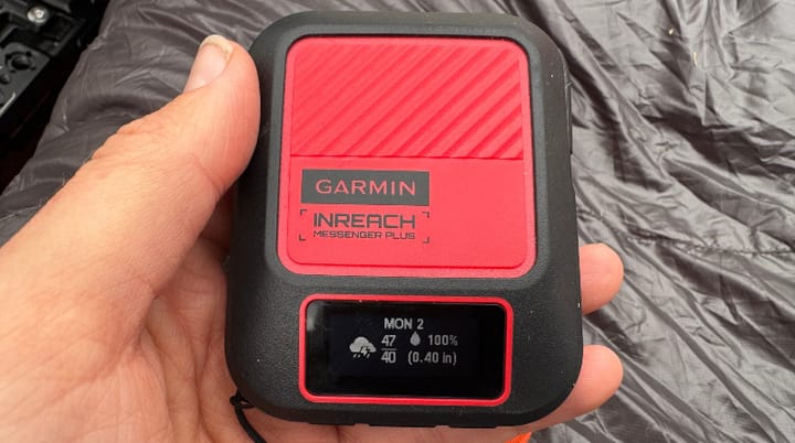  Garmin inReach Messenger Plus held in front of a rugged desert ridgeline under a clear blue sky, ready for off-grid adventure.