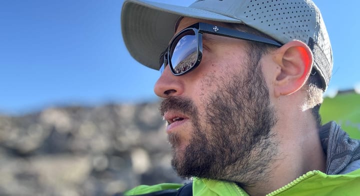 Hiker wearing FKT Gear Beaten Path Sunglasses with black frames and polarized lenses under mountain sunlight.