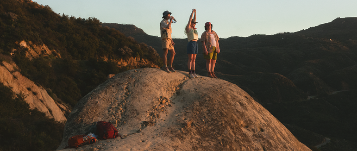 Group of hikers enjoying sunset views from a rocky peak, outfitted with gear available during the REI Labor Day Sale 2025.