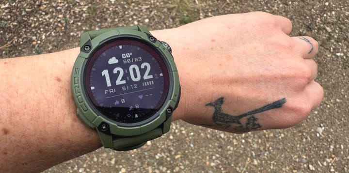 Green COROS Nomad GPS watch worn on wrist, showing digital time, weather, and fitness data on screen.