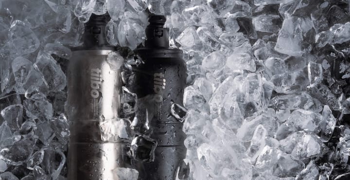Two Tiibo Vacuum Insulated Bottles, black and stainless steel, surrounded by ice cubes to highlight all-day cold retention.