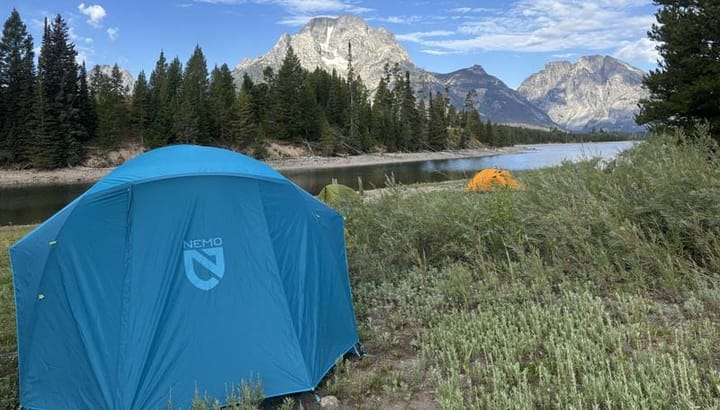 NEMO Equipment Aurora Highrise Camping Tent set up in a scenic campground at sunset, showing its tall walls and spacious interior design.