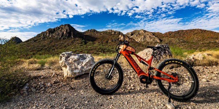 Bakcou 2025 Series off-road electric bike on a rugged mountain trail during the holiday sale, featuring $300 off, free battery, and free shipping promotion.