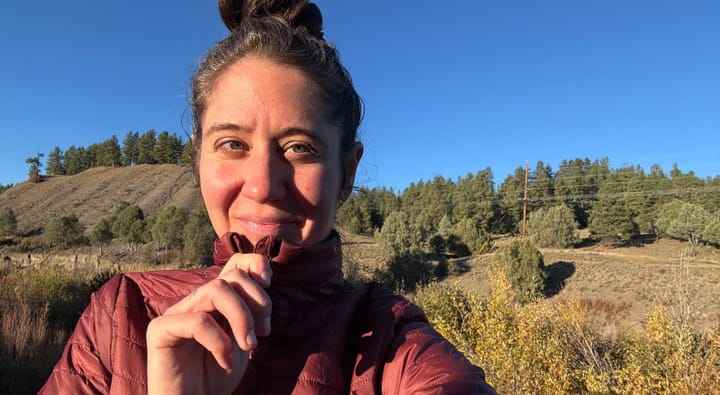 Woman wearing PAKA Mayu Ultralight Jacket in red during sunrise hike in Colorado mountains.