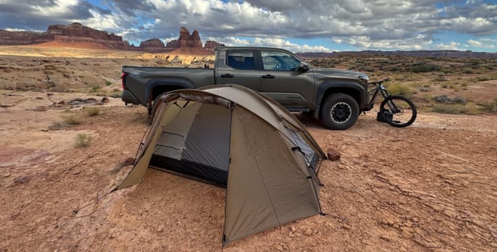 Snow Peak Minute Dome Pro Air 1 tent set up on red desert ground near a truck and mountain bike under cloudy skies.