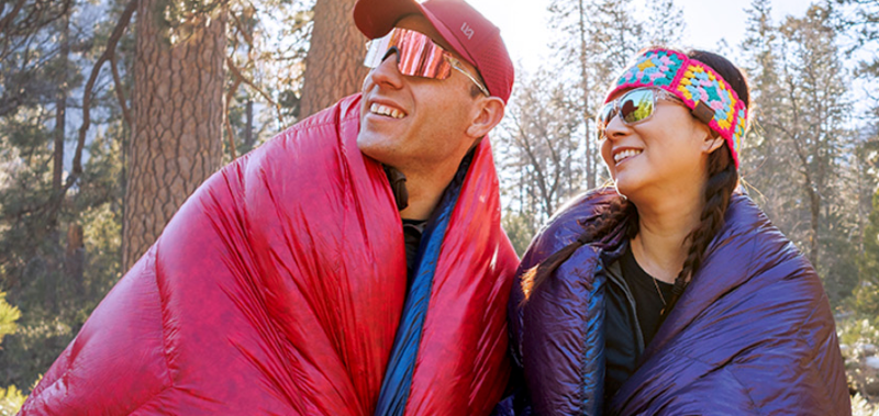 Backpacker using Enlightened Equipment quilt and ultralight gear on a mountain trail during the November Sale 2025, featuring 20% off all custom and in-stock gear.